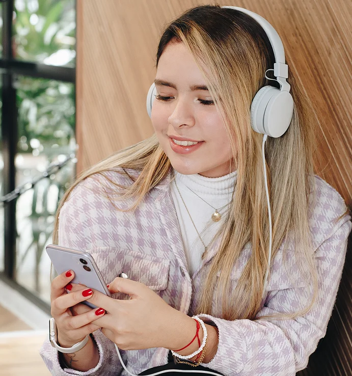 Estudiante con audífonos y celular en una especialización en supply chain con clases en vivo y grabadas
