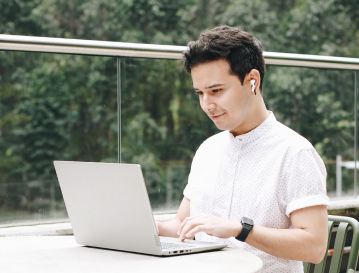 Hombre con portátil en una terraza: diplomado virtual de sostenibilidad en EAFIT Virtual